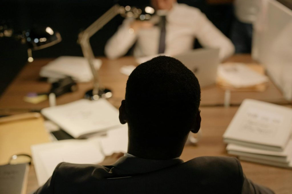 Back view of a professional in a workplace meeting with documents and laptops