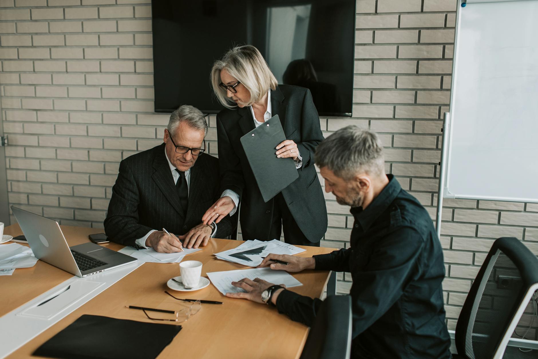 Business professionals in a meeting reviewing and signing legal documents