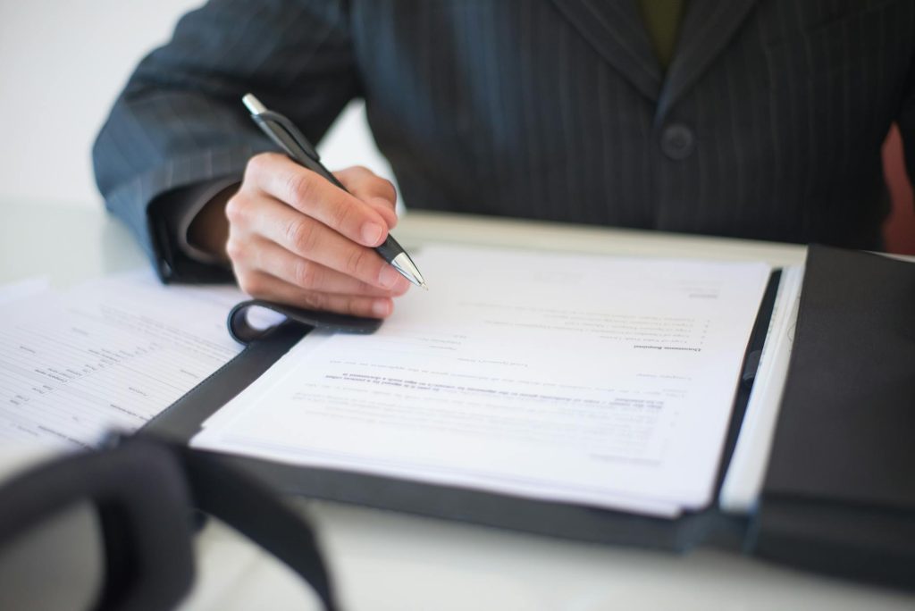 Close-up of a hand signing a financial contract document