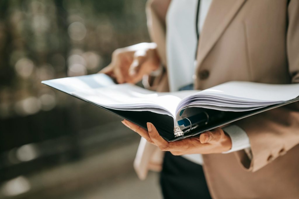 Anonymous professional reviewing pages of documents in a folder representing tax compliance review