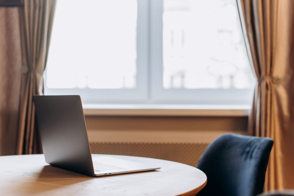 Modern laptop on a wooden table with window curtains in the background