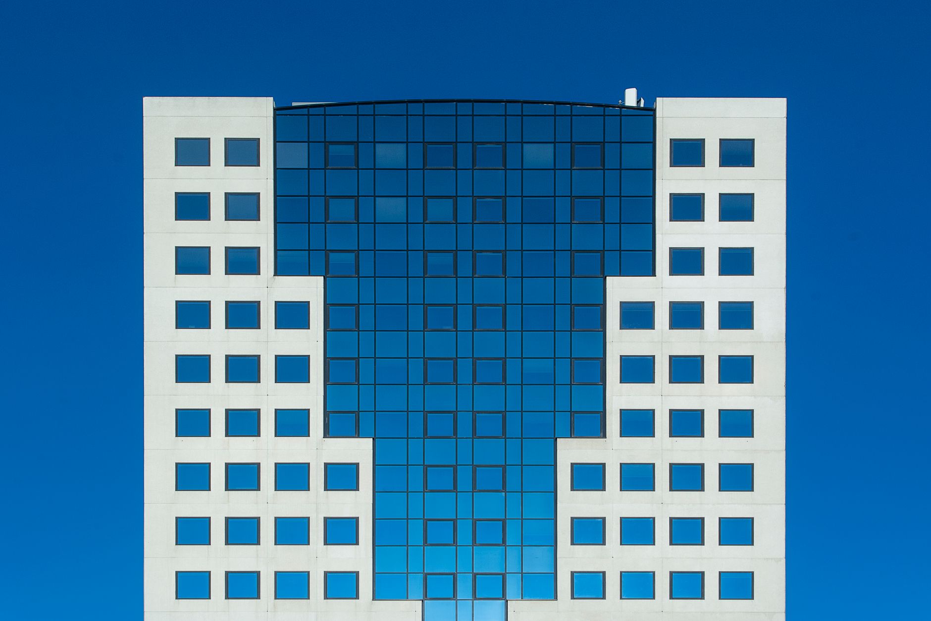 Modern office building with striking geometric facade against a clear blue sky
